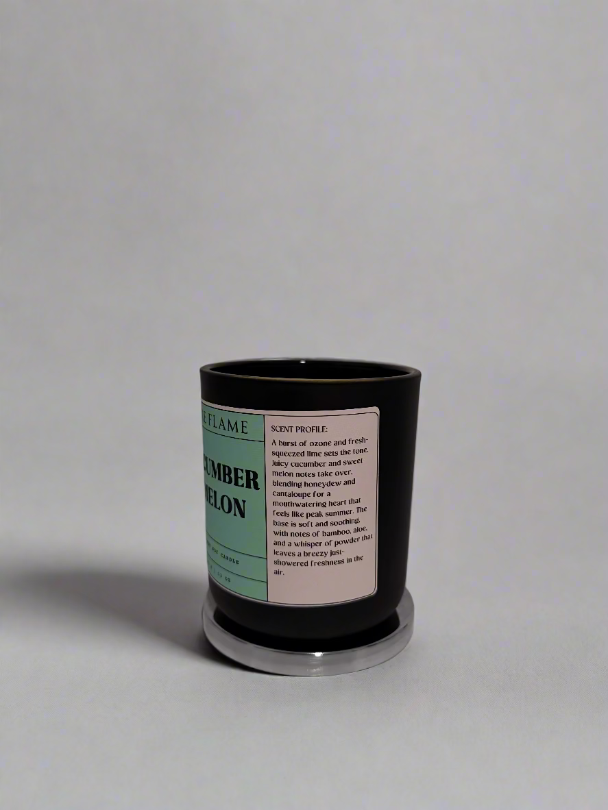 Black candle with a label on a white surface against a textured white wall