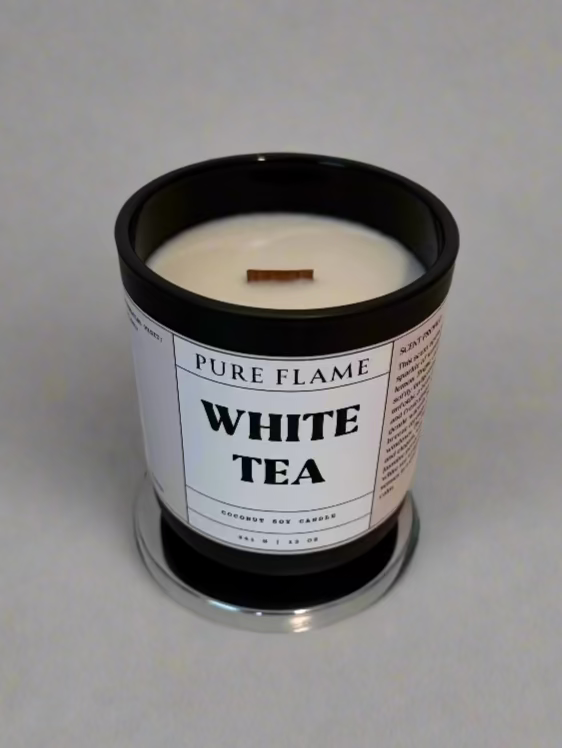 White tea candle in a black container on a white surface