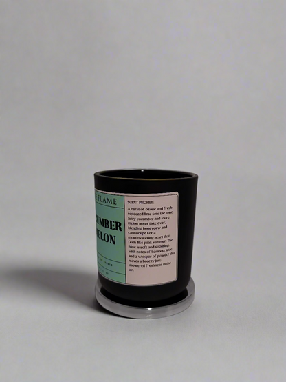 Black candle with a label on a white surface against a textured white wall