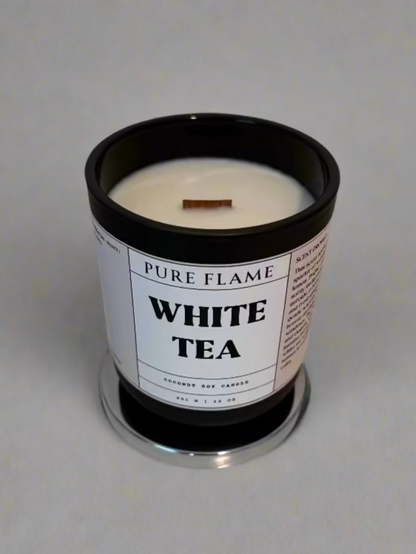 White tea candle in a black container on a white surface