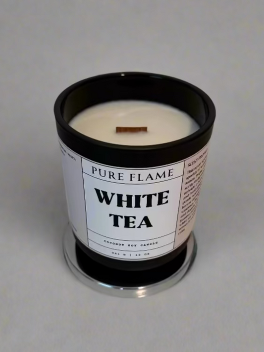 White tea candle in a black container on a white surface